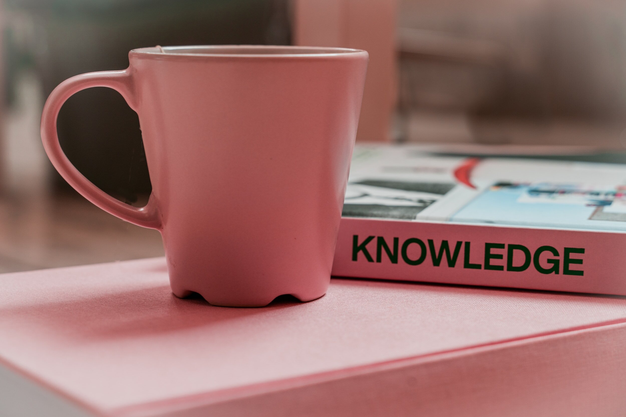Kranus Health: Rosa Tasse neben Buch mit Titel "Knowledge"