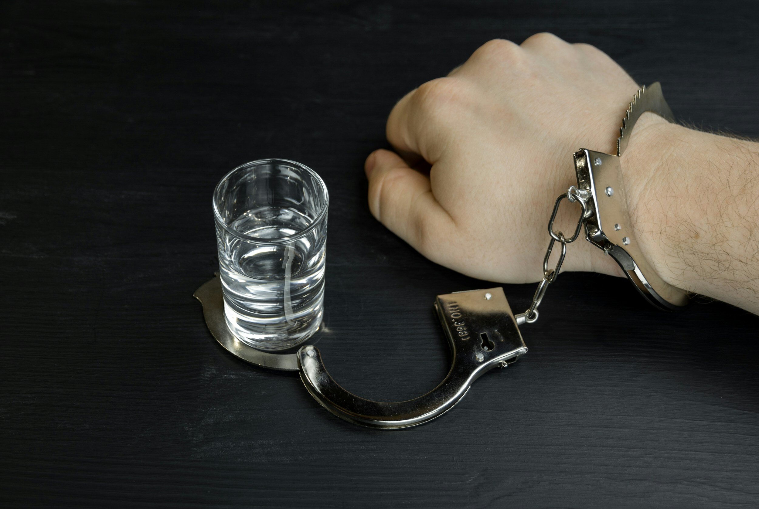 Kranus Lutera: Hand an Glas Wasser mit Handschelle