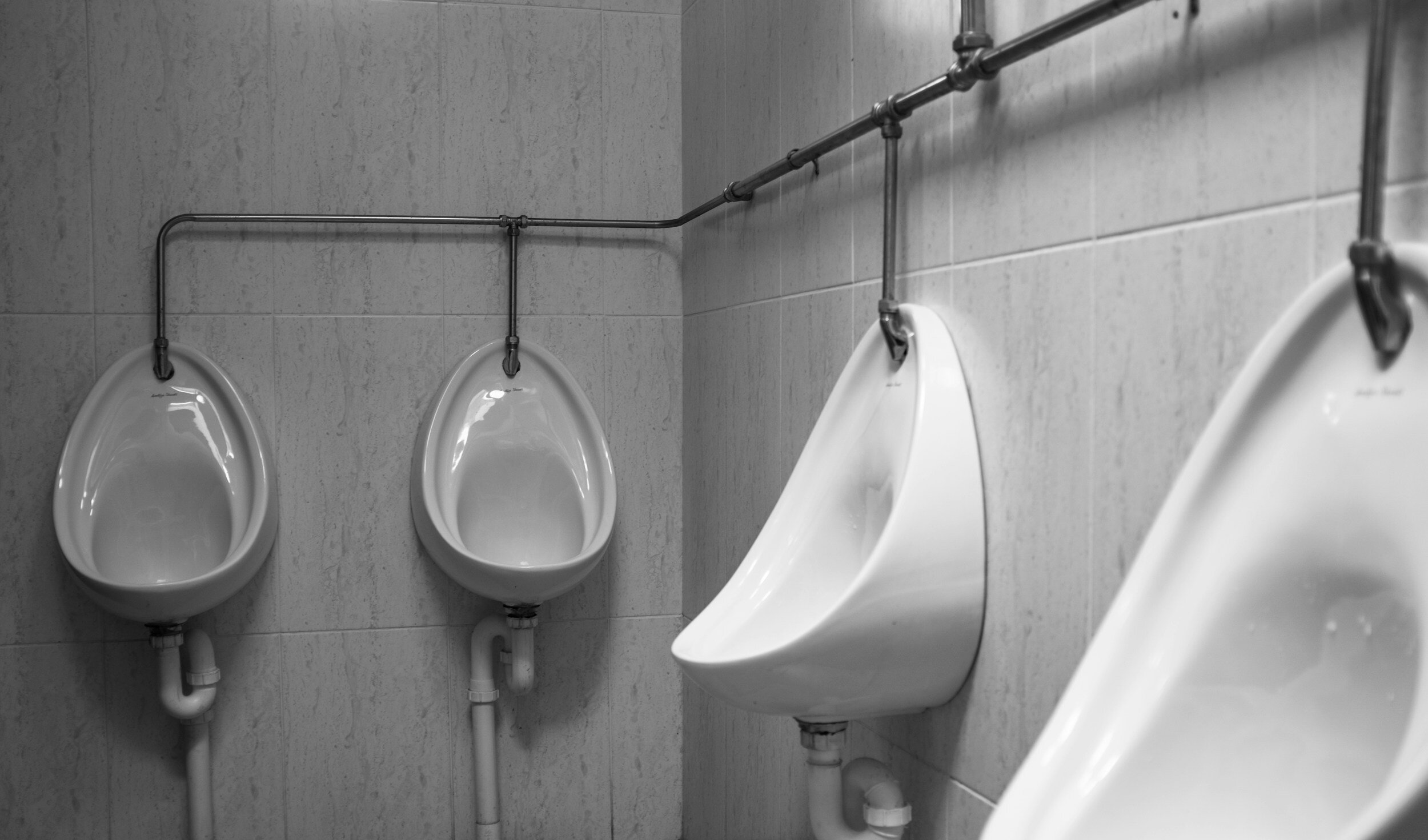 Kranus Lutera: Pissoirs vor weißer gefliester Wand