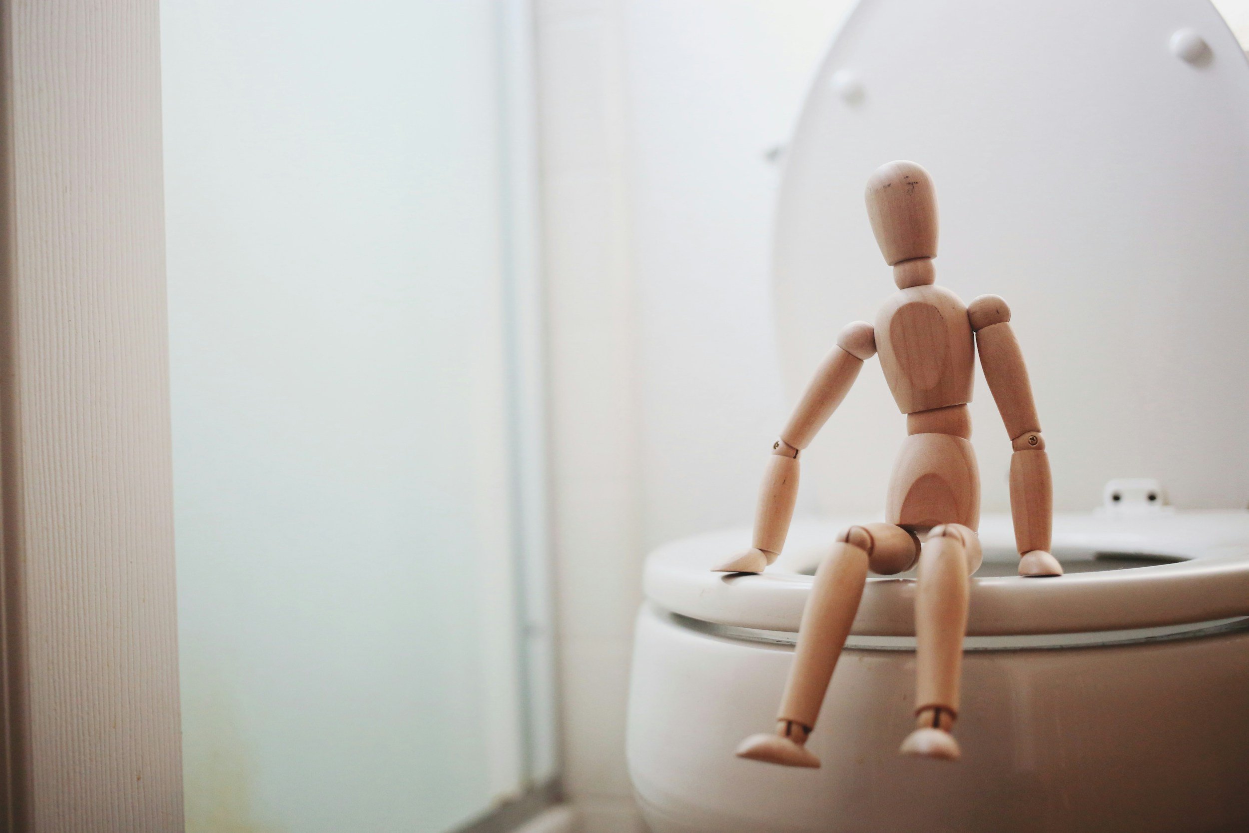 Kranus Lutera: kleiner Mann aus Holz sitzt auf Toilette